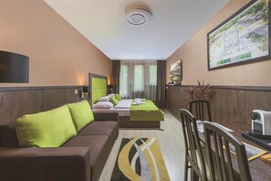 A hotel room with a bed, two sofas, a TV, a desk, and a large window. - Parl Hotel Bükfürdő (Buk)