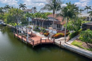A waterfront property with a dock, palm trees, and a house with a red roof. - Marco Island Antigua Villa • Dock • Walk to Beach (Marco Island)