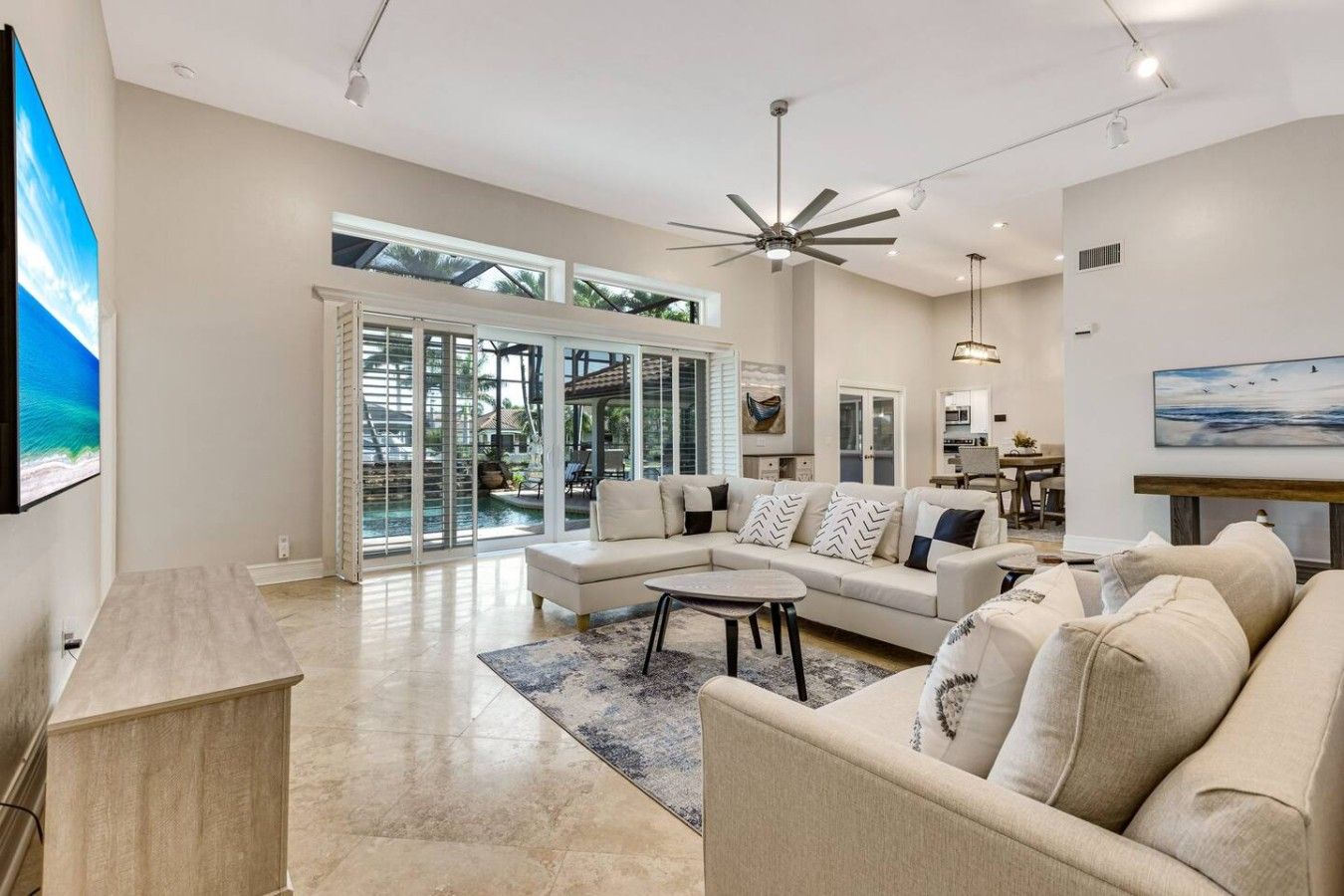 A spacious living room with a large sectional sofa, a coffee table, and a ceiling fan.