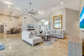 A spacious living area with a large L-shaped sofa, a dining table with chairs, and a ceiling fan. - Marco Island Antigua Villa • Dock • Walk to Beach (Marco Island)