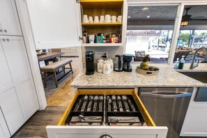 A kitchen with a drawer organizer containing utensils, a coffee maker, and a fruit bowl on the counter.