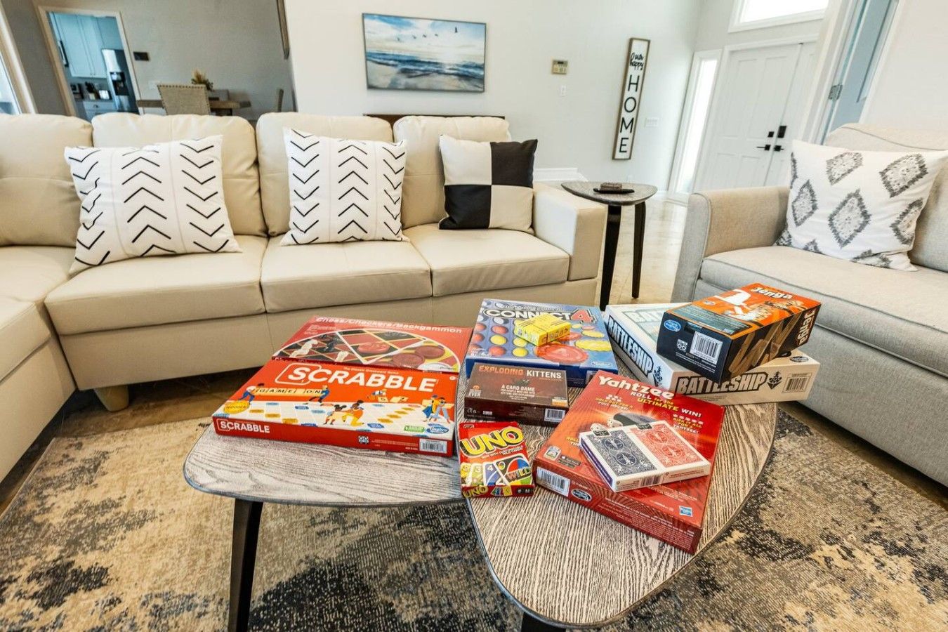 A living room with a sofa, a coffee table with board games, and a wall with a 'HOME' sign.