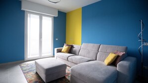 A living room with a grey sofa, a matching ottoman, and a colorful rug.