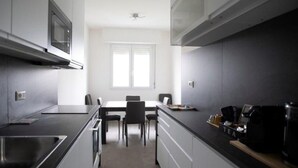 A modern kitchen with a built-in microwave, a dining table with chairs, and a coffee machine on the counter.