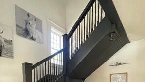 Una escalera con barandillas de madera oscura y un suelo a cuadros.