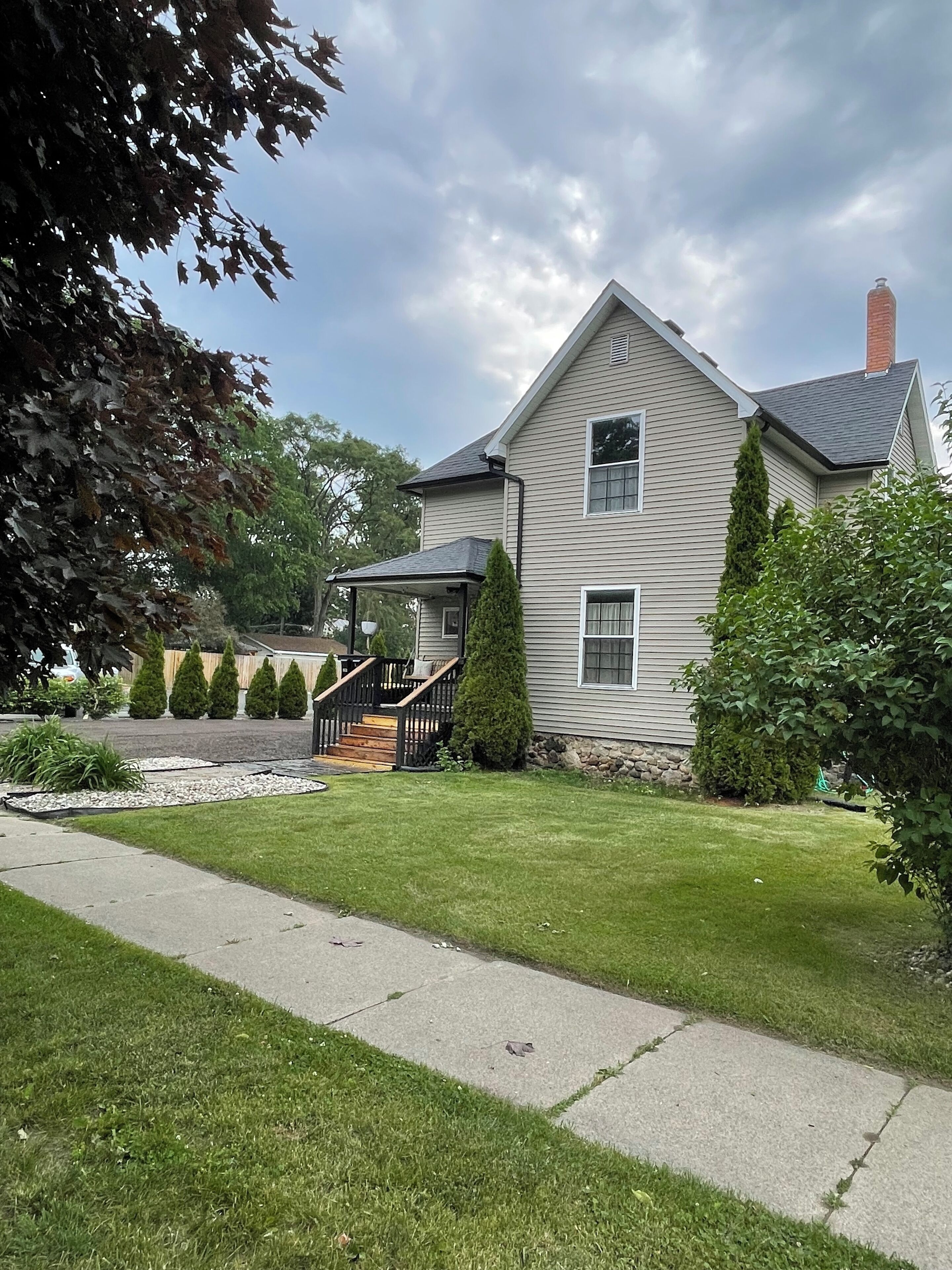 A two-story house with a front porch, a stone foundation, and a well-maintained lawn.