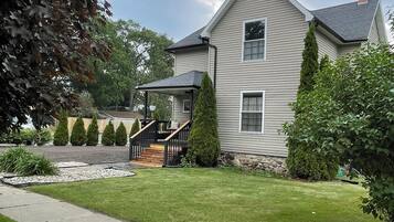 A two-story house with a front porch, a stone foundation, and a well-maintained lawn.