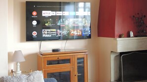 A flat-screen TV mounted on a wall displaying various streaming services and TV channels. -     Καλώς ήρθατε στη βάση των διακοπών σας. (Κόρινθος)