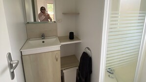 Un baño pequeño con espejo, lavamanos y un mueble auxiliar.