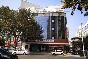 A modern building with a glass facade, a storefront with signage, and a street with cars and trees. - Homeinn Plus Hotel (Qingdao Weihai Road Taidong Pedestrian Street) (Qingdao)