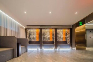 A modern lobby with a seating area, a wall with a patterned design, and a reception desk. - Homeinn Plus Hotel (Qingdao Weihai Road Taidong Pedestrian Street) (Qingdao)