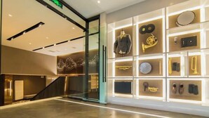 A modern interior with a glass wall, a staircase, and a display of musical instruments and accessories. - Homeinn Plus Hotel (Qingdao Weihai Road Taidong Pedestrian Street) (Qingdao)