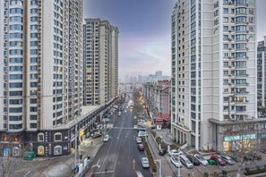 A multi-story building with a central road, parked cars, and a clear sky. - Homeinn Plus Hotel (Qingdao Weihai Road Taidong Pedestrian Street) (Qingdao)