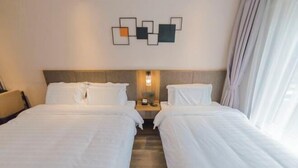 A hotel room with two beds, a headboard, a wall-mounted light fixture, and a window with curtains. - Homeinn Plus Hotel (Qingdao Weihai Road Taidong Pedestrian Street) (Qingdao)