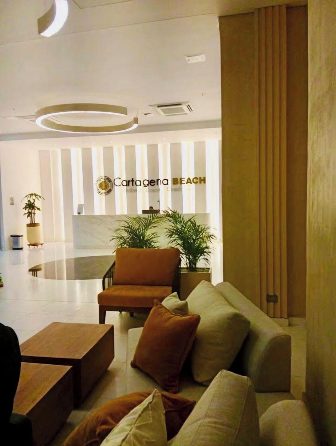 A modern lobby with a reception desk, a sofa, a chair, and a coffee table.