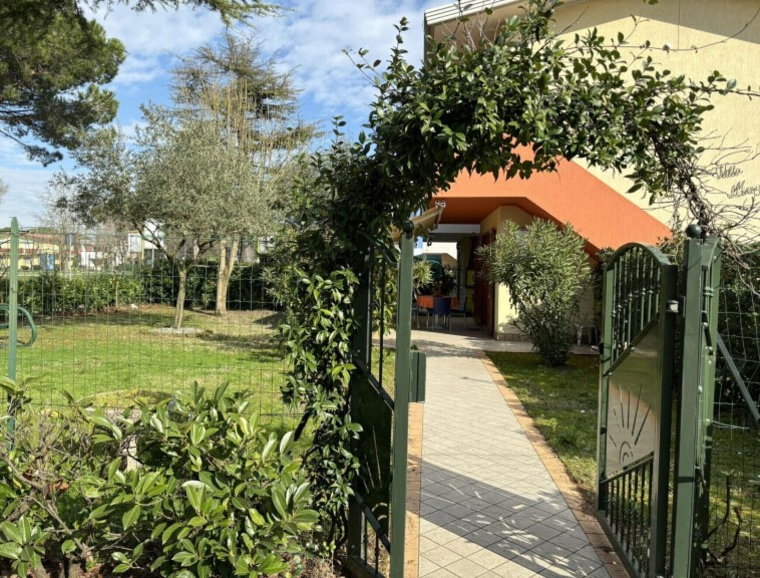 Un camino que lleva a un edificio con una puerta verde y un acceso cubierto.