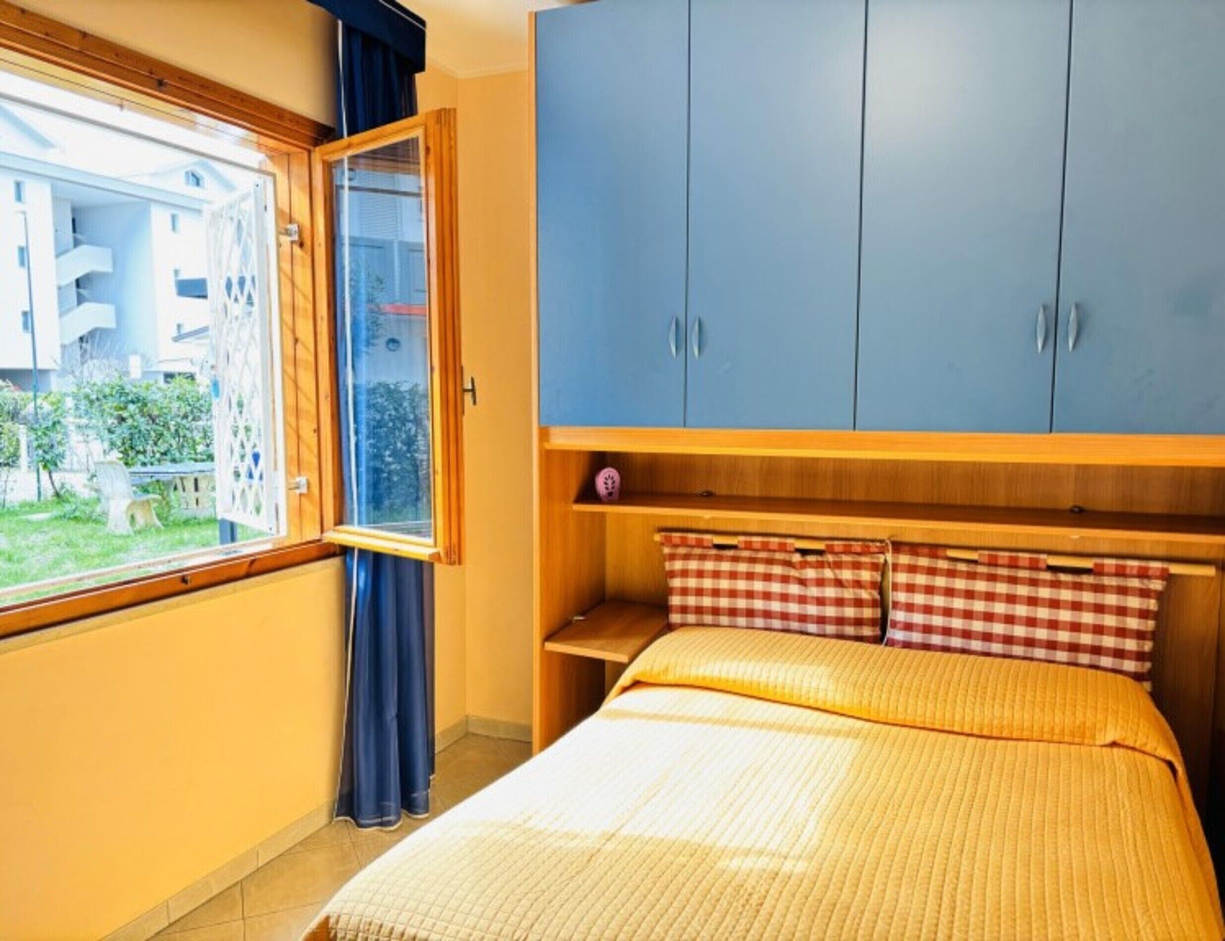 A bedroom with a bed, a window, and a blue wardrobe.