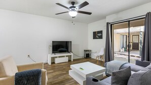 A modern living room with a flat-screen TV, a ceiling fan, and a large window with curtains. - Baton Rouge-Pet friendly, 2BR/2BA, Near LSU (Baton Rouge)