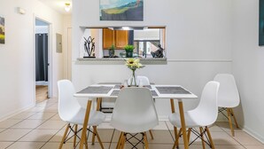 A dining area with a table, four white chairs, and a vase with flowers. - Baton Rouge-Pet friendly, 2BR/2BA, Near LSU (Baton Rouge)