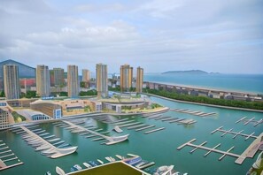 Una marina con barcos, un puente y edificios altos al fondo.