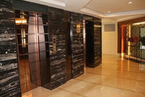 A modern hotel lobby with marble walls, a polished floor, and a reception area. - Ocean Holiday Apartment (Lingshui)