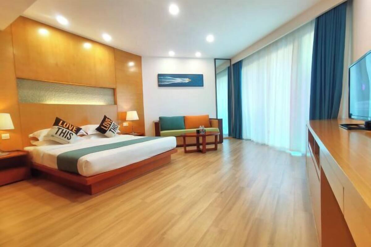 A hotel room with a large bed, a desk, a chair, and a TV.