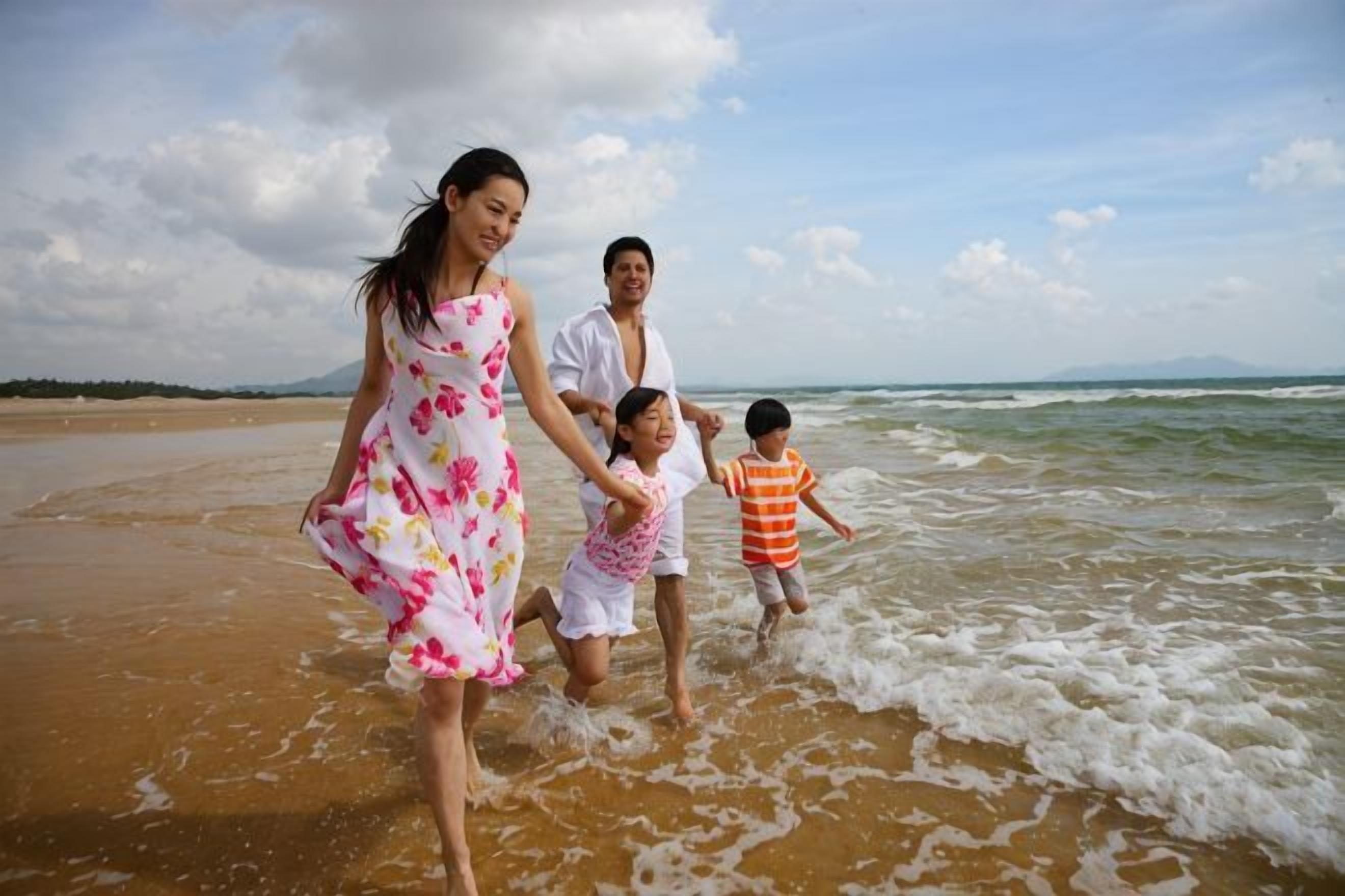 A beach scene with a family running along the shore.