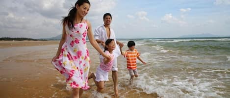 Une scène de plage où l’on voit une famille courant le long du rivage.