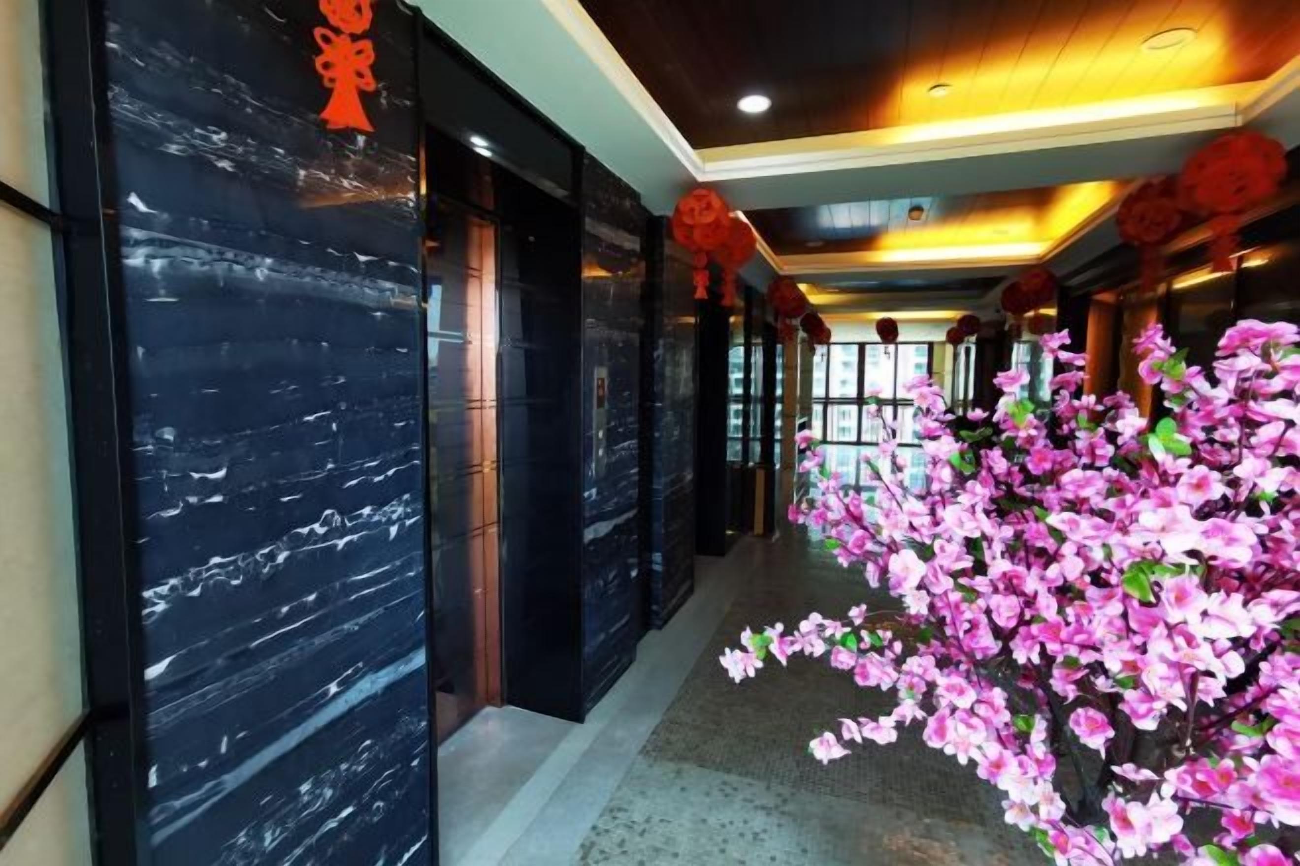 A hallway with a black marble wall and a pink floral display.