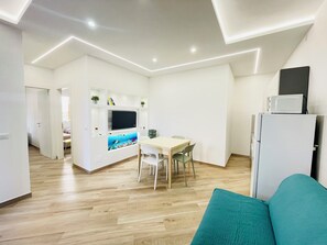 Cozinha moderna com área de jantar, TV fixada na parede e geladeira.