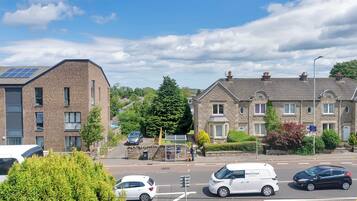 A residential street with houses, a bus stop, and parked cars.