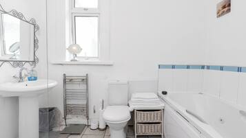 A bathroom with a sink, mirror, toilet, and bathtub.