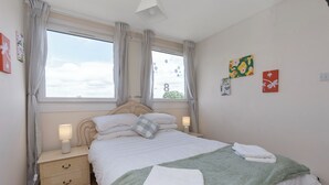 A bedroom with a bed, bedside tables, a window with curtains, and wall art. - Room-edinburgh Bungalow Royal Infirmary (Edinburgh)