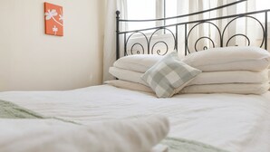 A neatly made bed with white bedding and a checkered pillow, a metal headboard, and a wall with a framed picture. - Room-edinburgh Bungalow Royal Infirmary (Edinburgh)