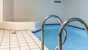 Una piscina con barandillas de metal y suelo de baldosas.