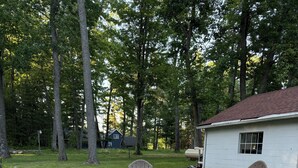 A backyard with a fire pit, two Adirondack chairs, and a small shed. - Cozy acorn cottage w/ lake view (West Branch)