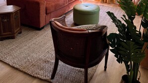 A living room with a sofa, a chair, a television, and a ceiling fan. - Cozy acorn cottage w/ lake view (West Branch)