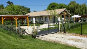 A two-story building with a covered patio, a fenced area, and a gravel driveway.
