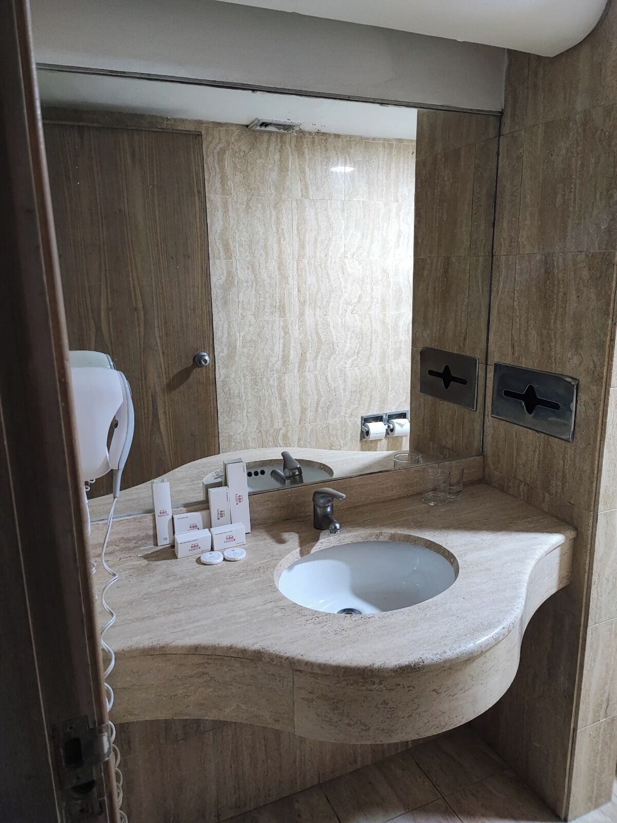 A modern bathroom with a curved sink, a mirror, and a hairdryer.