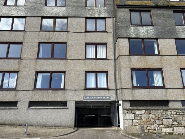 A multi-story building with a stone facade, multiple windows, and a gated entrance labeled "CARRACK WIDENED FLATS".