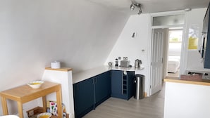 A compact kitchen with a dining area, featuring a small table, chairs, and a counter with appliances.