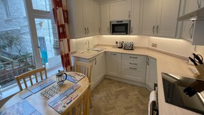 A compact kitchen with white cabinets, a microwave, a toaster, and a sink.