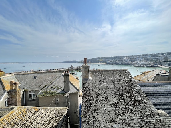 Un pueblo costero con edificios de piedra, un puerto y barcos.