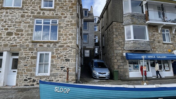 A stone building with a sign 'ST BRIGIDS' and a car parked in front.