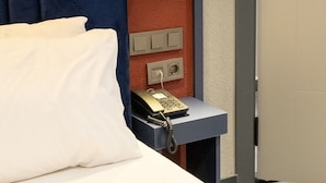Ein Hotelzimmer mit einem Bett, einem Nachttisch mit Lampe und einem Telefon.