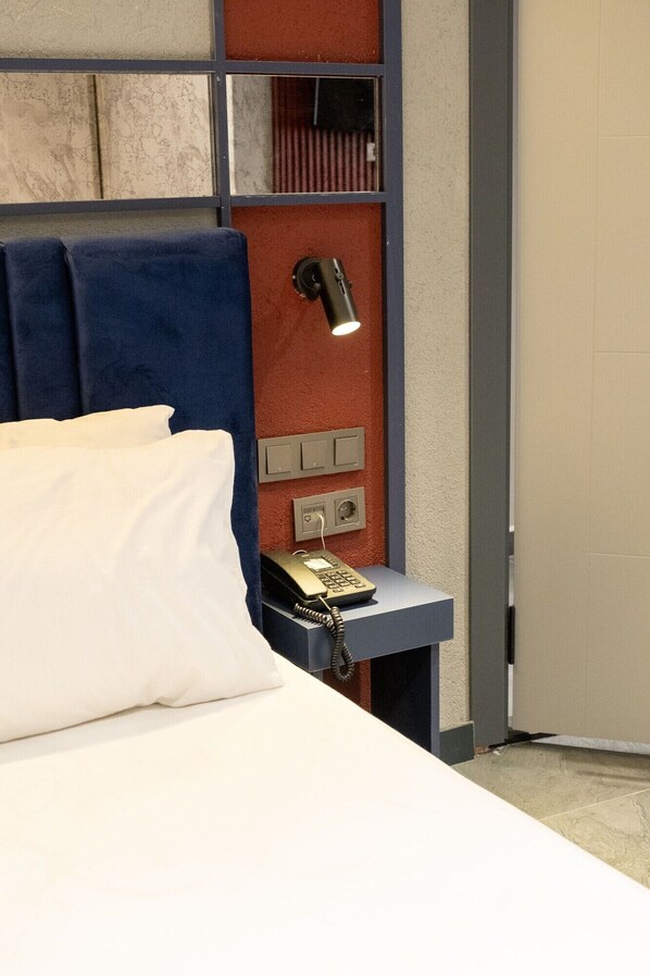 Een hotelkamer met een bed, een nachtkastje met lamp en een telefoon.
