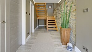 A modern interior with a wooden staircase, a stone wall, and a large potted plant. - The Gate House (Richmond)