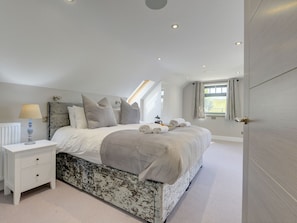 A bedroom with a large bed, a nightstand, a lamp, and a window with curtains. - The Gate House (Richmond)