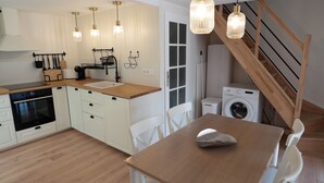 Cocina moderna con armarios blancos, encimera de madera y luces colgantes.