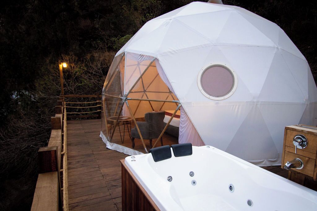 Estructura en forma de domo geodésico con un jacuzzi en primer plano.